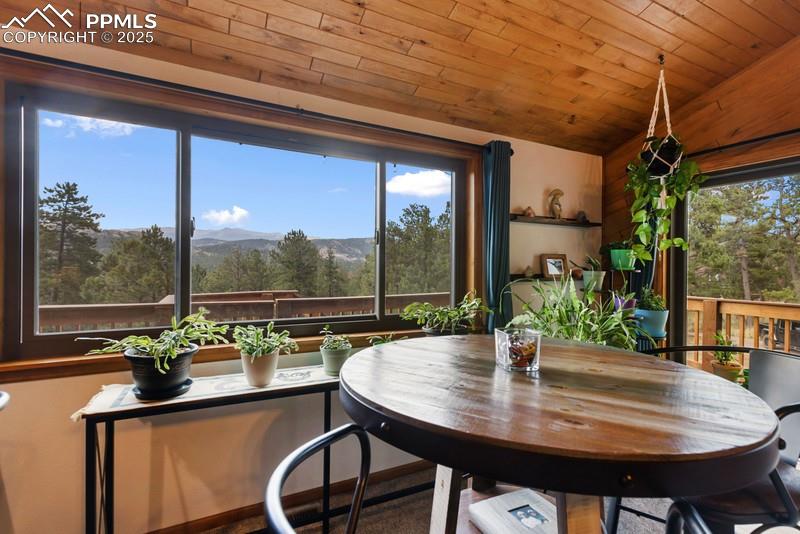 Image 19 of 37: Dining space with a mountain view and wood ceiling