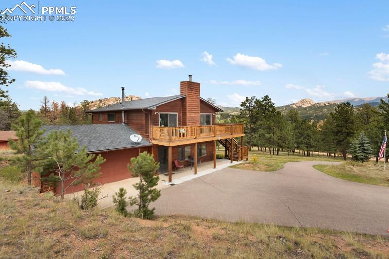 Image 2 of 37: Rear view of house featuring stairway, asphalt driveway, a patio area, a de