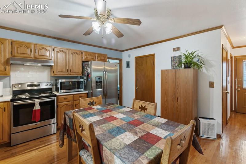 Image 21 of 37: Kitchen with appliances with stainless steel finishes, crown molding, light