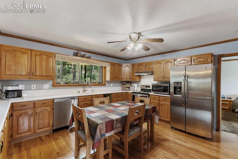 Image 22 of 37: Kitchen with stainless steel appliances, light countertops, ornamental mold