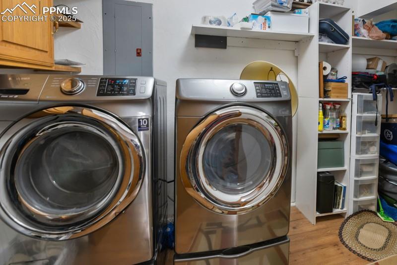 Image 31 of 37: Laundry room with light wood-type flooring, electric panel, and washer and