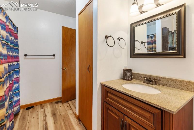 Image 33 of 37: Full bath featuring light wood finished floors, vanity, and a shower with c