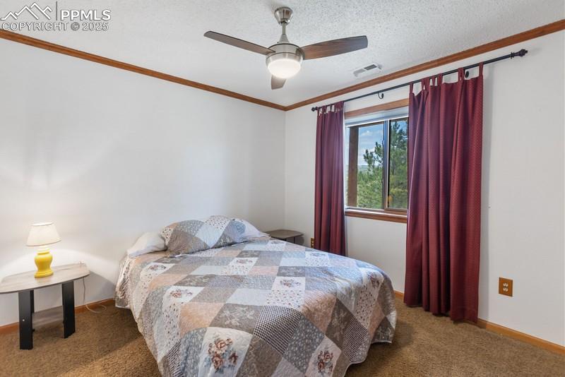 Image 34 of 37: Carpeted bedroom featuring a textured ceiling, a ceiling fan, and crown mol