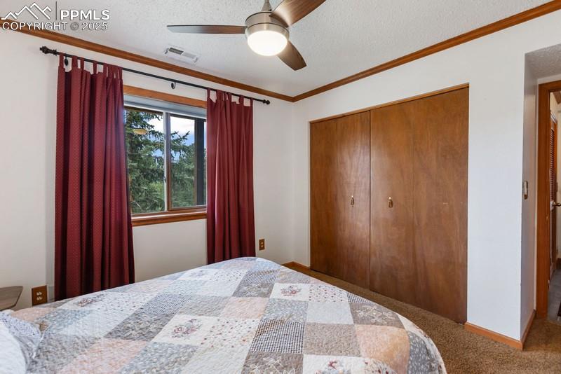 Image 35 of 37: Carpeted bedroom featuring a textured ceiling, crown molding, a ceiling fan
