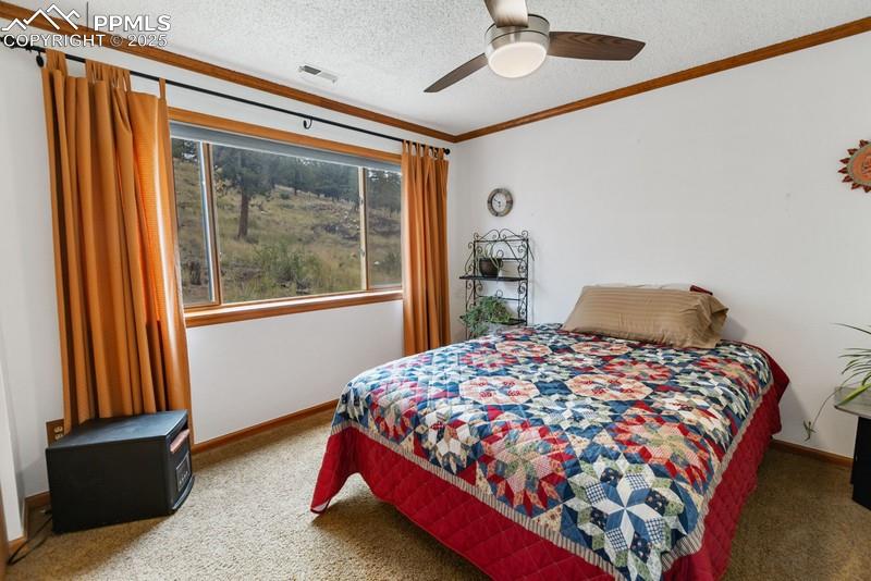 Image 36 of 37: Bedroom featuring carpet floors, a textured ceiling, ceiling fan, and ornam