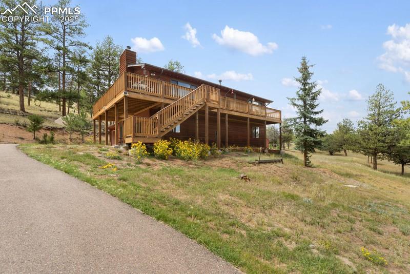 Image 4 of 37: Back of house featuring a wooden deck, a chimney, and stairway