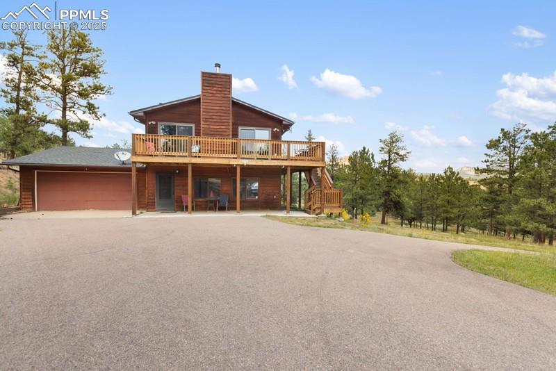 Image 5 of 37: Back of house featuring a deck, asphalt driveway, an attached garage, a pat
