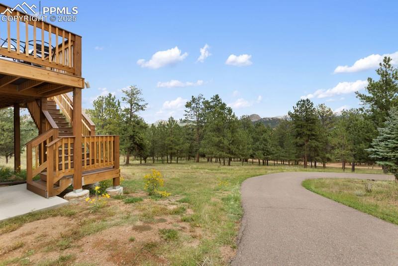Image 8 of 37: View of green lawn with a deck, stairs, and a rural view