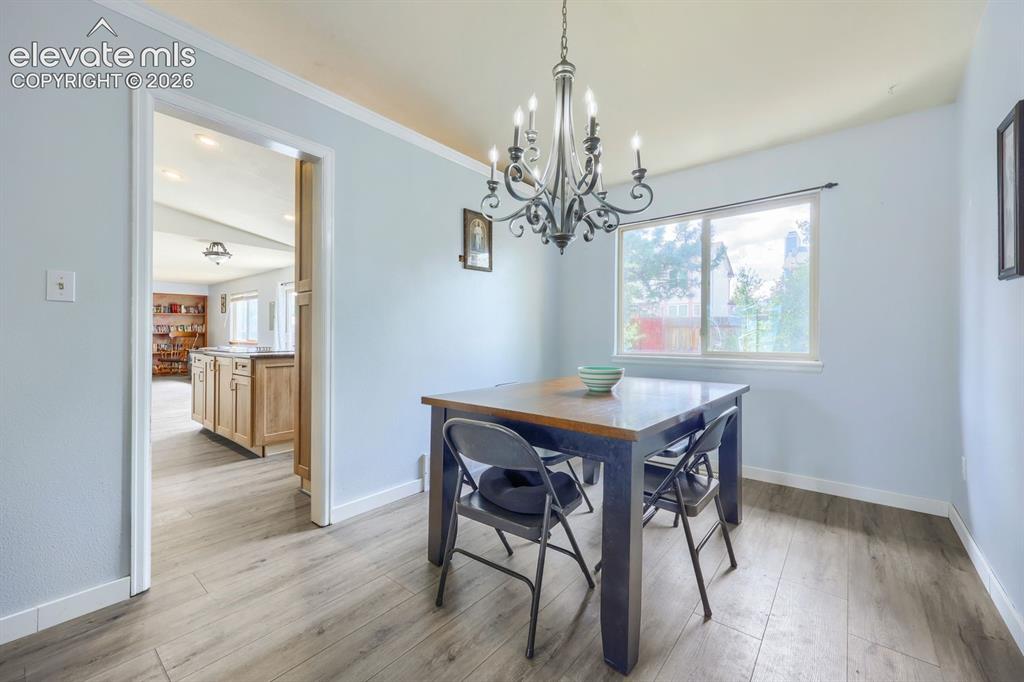 Image 11 of 42: Wood-finish flooring throughout, with a classic chandelier fixture and whit