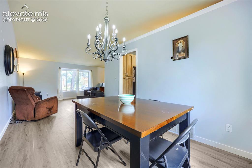 Image 12 of 42: Chandelier lighting, wood-finish flooring, and white crown molding
