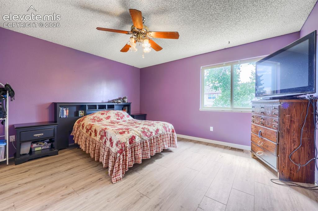 Image 13 of 42: LVP flooring with a neutral tone, overhead ceiling fan, and a built-in head