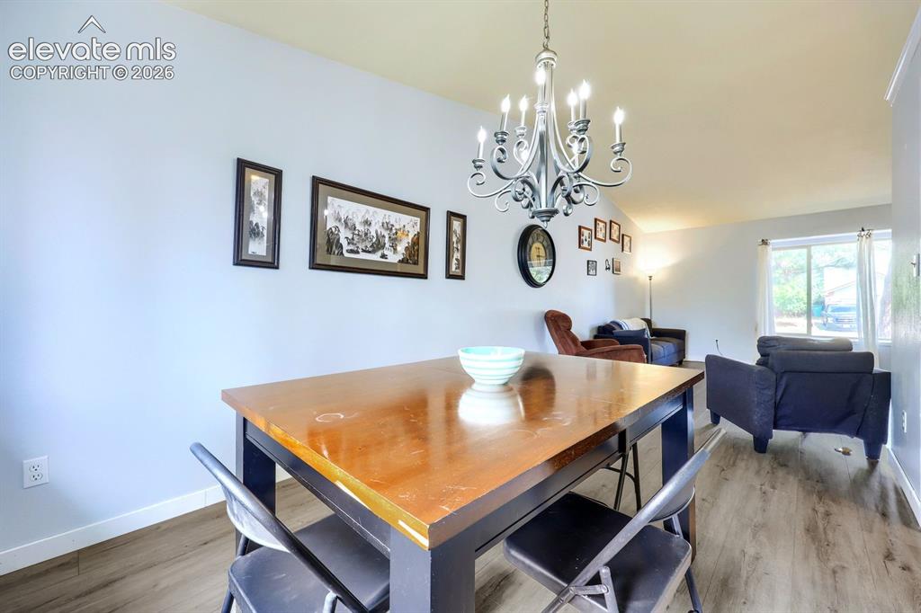 Image 13 of 42: Dining area with wood-finish flooring, featuring a classic chandelier and l