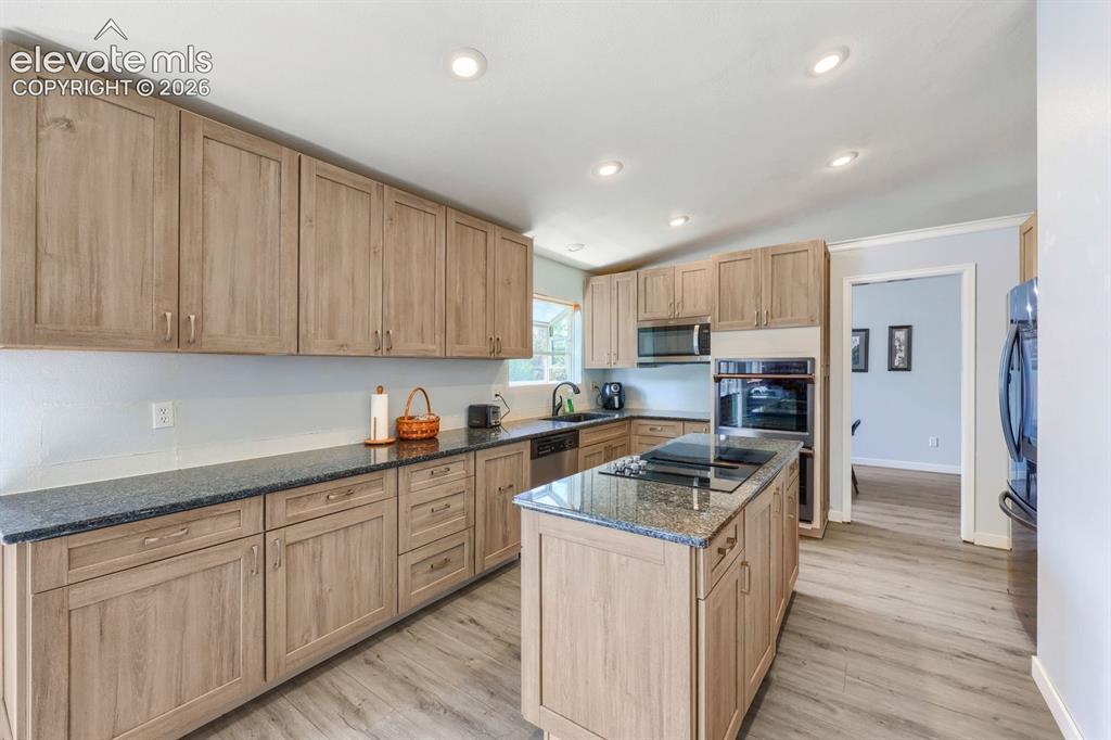 Image 14 of 42: Kitchen featuring wood-finish cabinetry, dark countertops, a center island