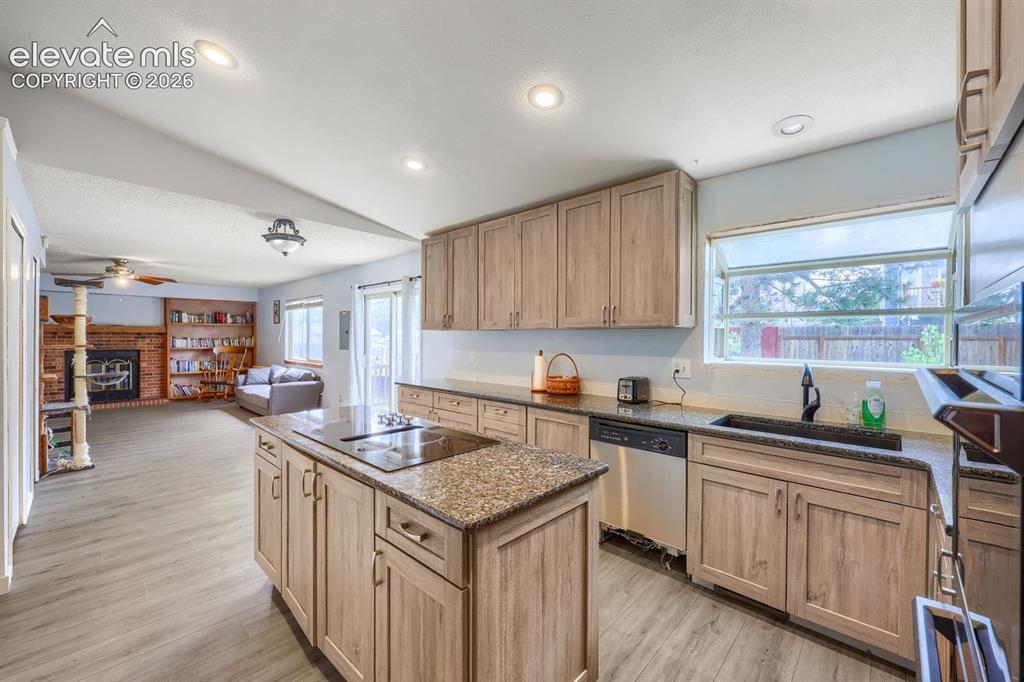 Image 15 of 42: Kitchen featuring an island with built-in cooktop, light wood-finish cabine