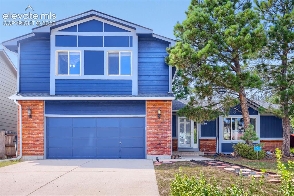 Image 2 of 42: Two-story exterior with blue siding and brick accents