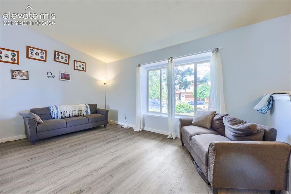 Image 21 of 42: Wood-finish flooring with a light tone, vaulted ceiling, and dual-pane wind