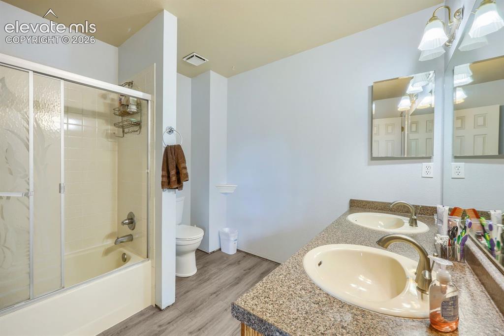 Image 27 of 42: Dual vanity with integrated sinks, brushed nickel fixtures, wood-finish flo