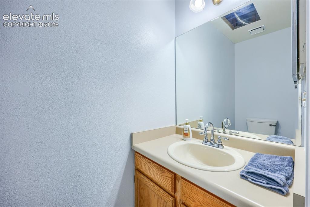 Image 28 of 42: Single vanity with a laminate countertop, integrated sink, and wood-finish