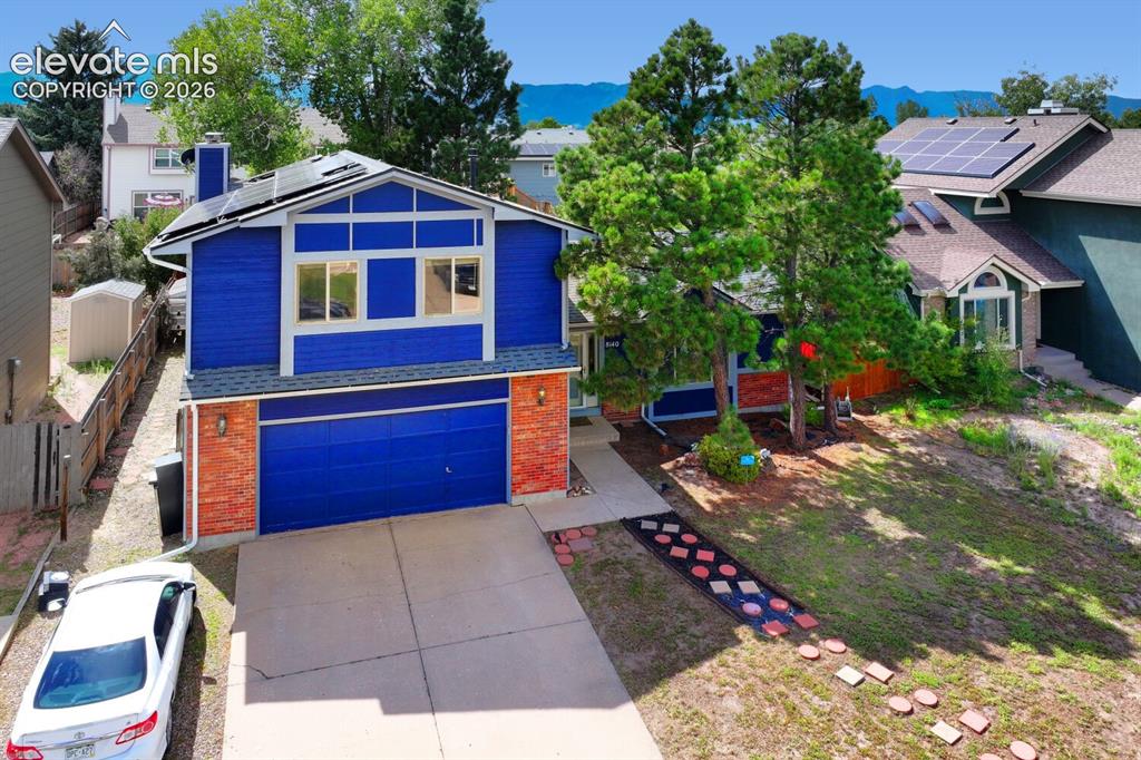 Image 34 of 42: Striking blue exterior with brick accents and integrated two-car garage