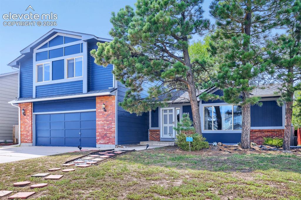 Image 36 of 42: Two-story residence featuring a blue siding exterior, brick accents, and an