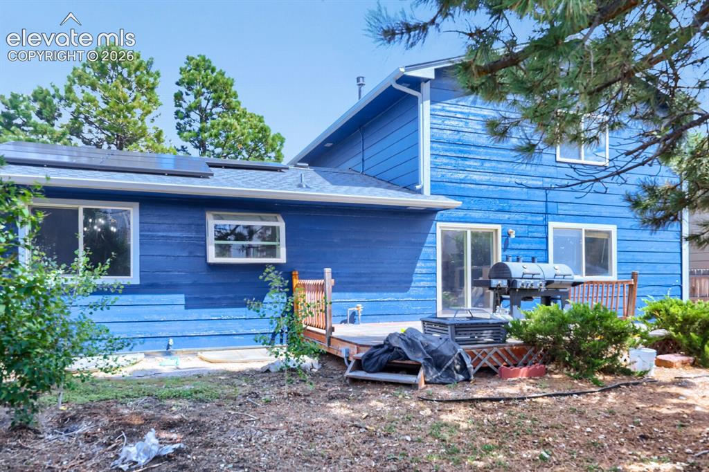 Image 38 of 42: Rear exterior with blue siding, multiple windows, sliding glass doors, and