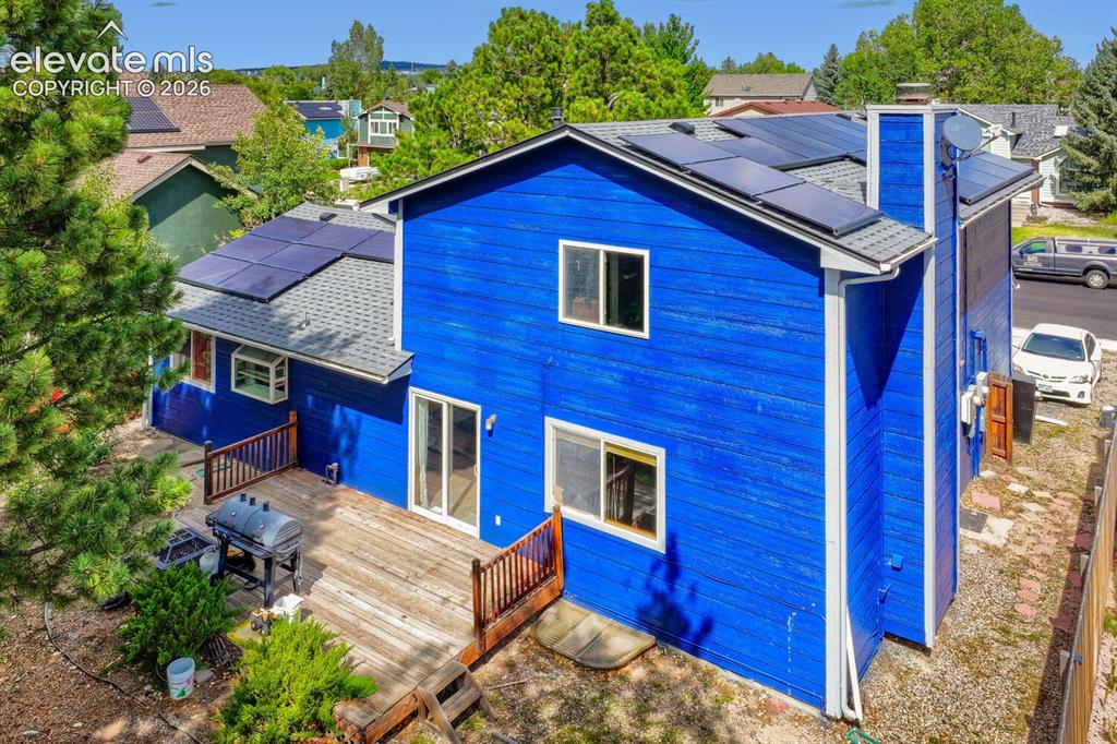 Image 39 of 42: Rear exterior featuring blue siding, a multi-level wood deck, multiple sola