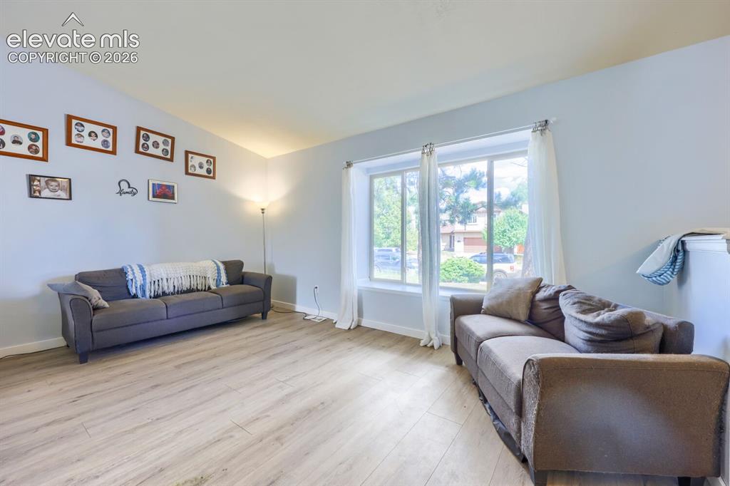 Image 6 of 42: Vaulted ceiling, light wood-finish flooring, and large windows