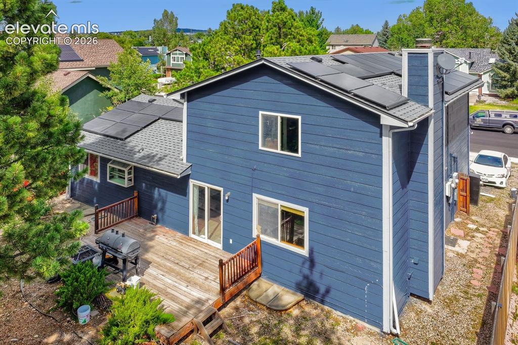 Image 7 of 42: Rear exterior featuring a wood deck, sliding glass doors, multiple windows,