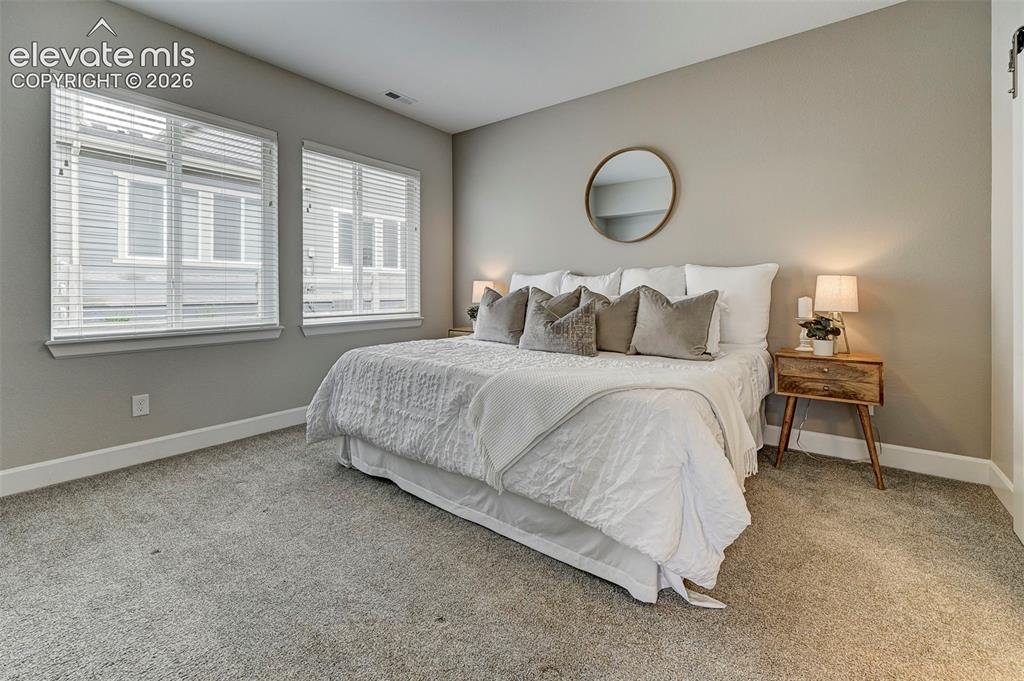Image 16 of 37: The main-floor primary bedroom is spacious and bright, with plenty of natur
