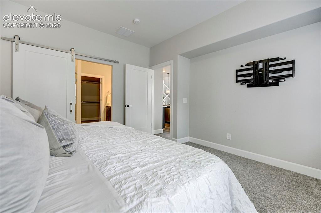 Image 18 of 37: Barn doors separate the primary bedroom from the ensuite bath. 