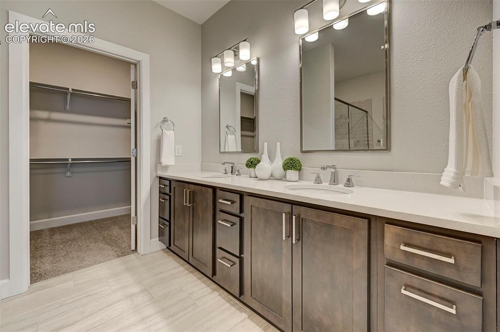 Image 21 of 37: Tile flooring, quartz countertops and undermount sinks make the primary bat