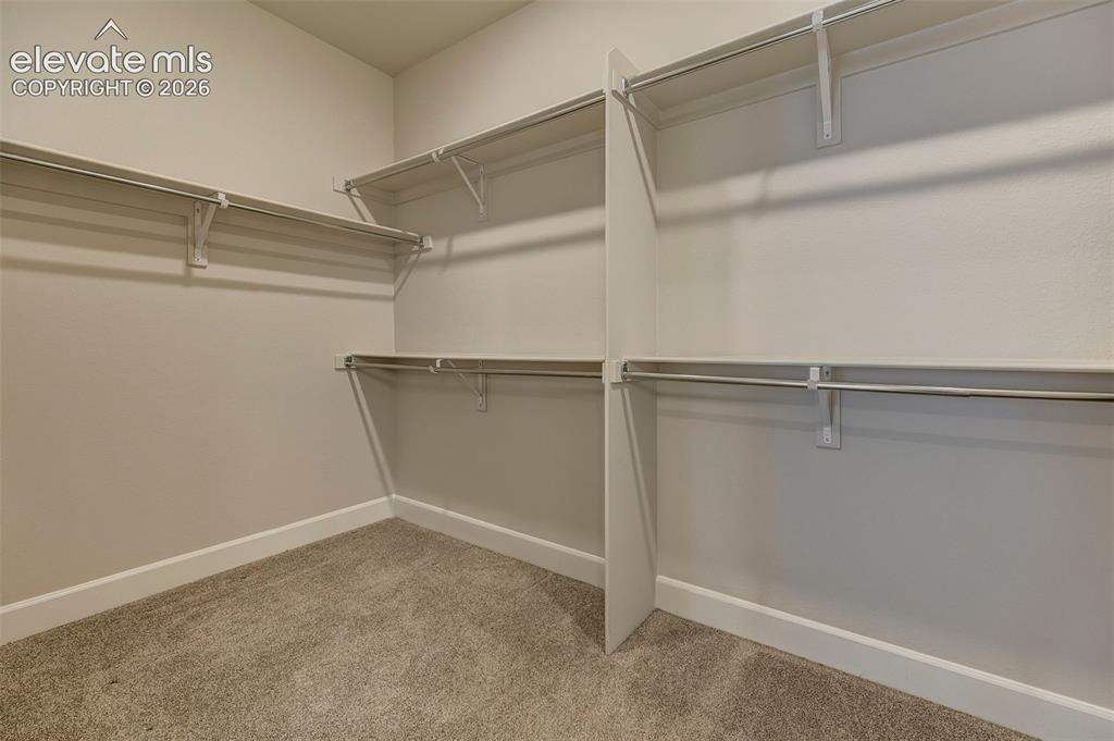 Image 22 of 37: The primary closet is spacious and features solid shelving and accessible h