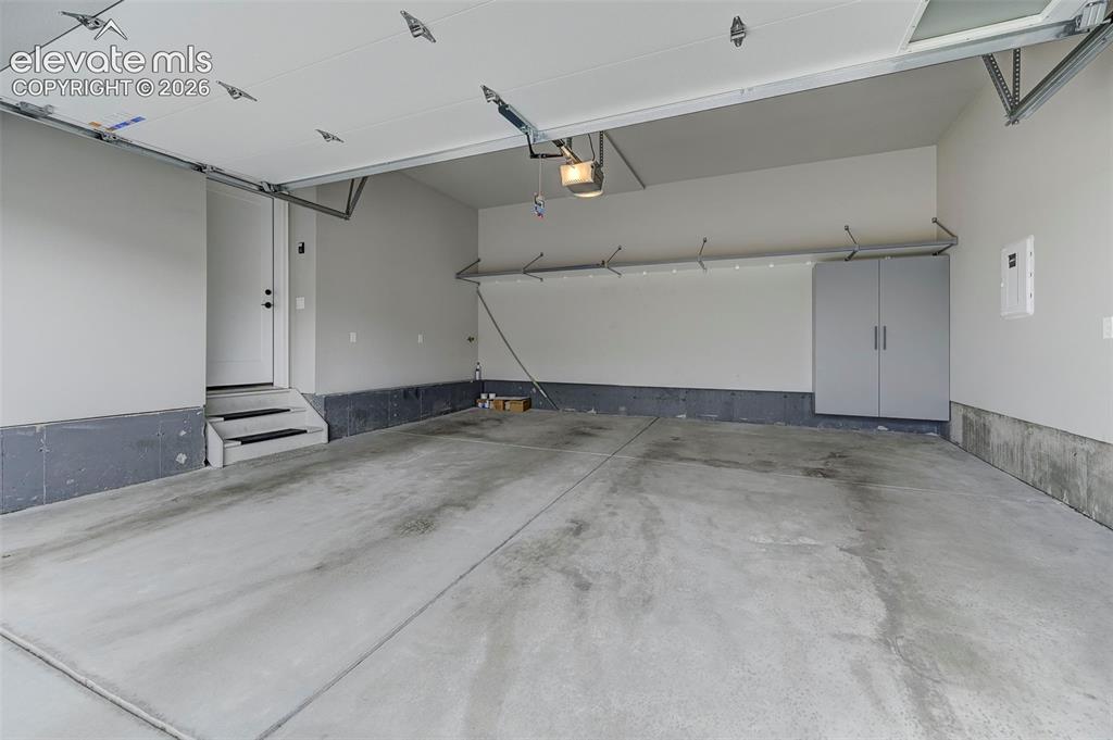 Image 33 of 37: The attached two-car garage has a built-in storage cabinet and wall-mounted