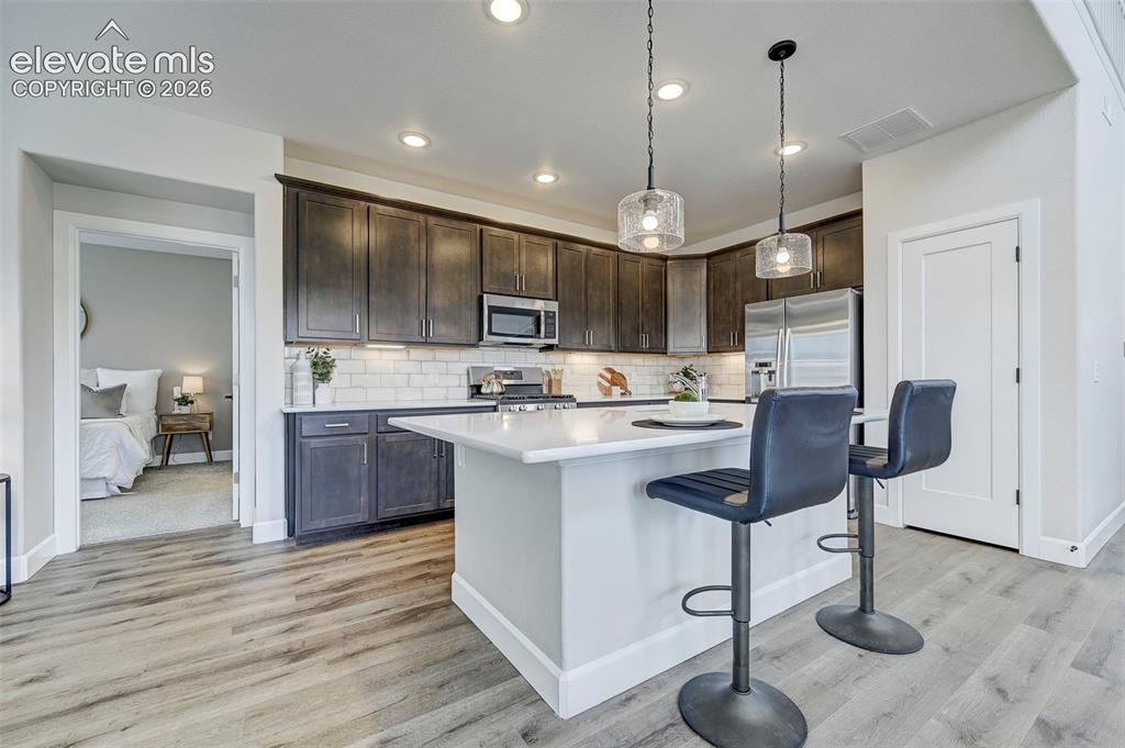 Image 9 of 37: Pendant lighting accents the spacious island, and a large pantry is just be