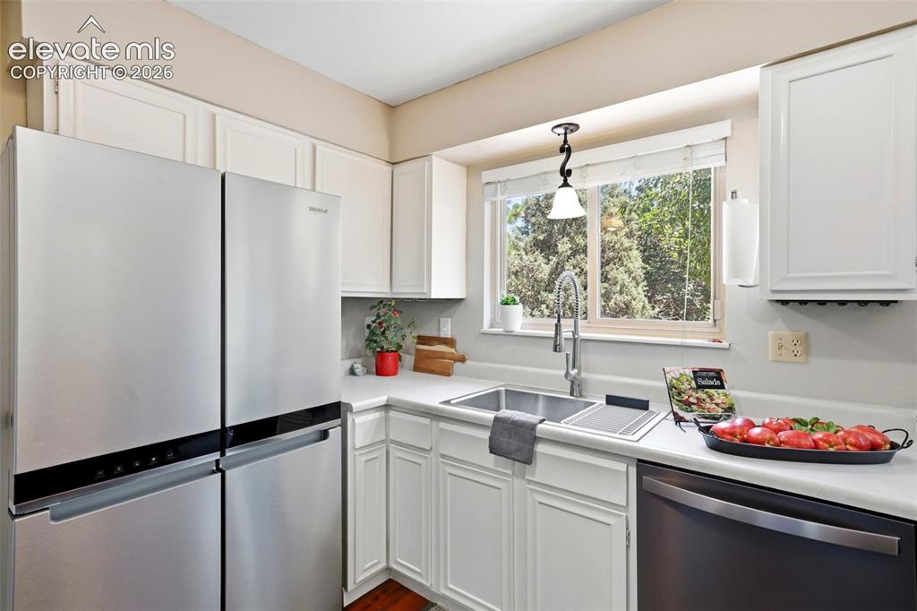 Image 11 of 50: Kitchen featuring white cabinetry, light countertops, stainless steel appli
