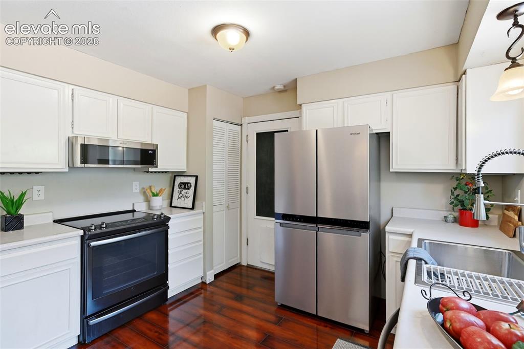 Image 14 of 50: Kitchen featuring white cabinetry, light countertops, wood-finish flooring,