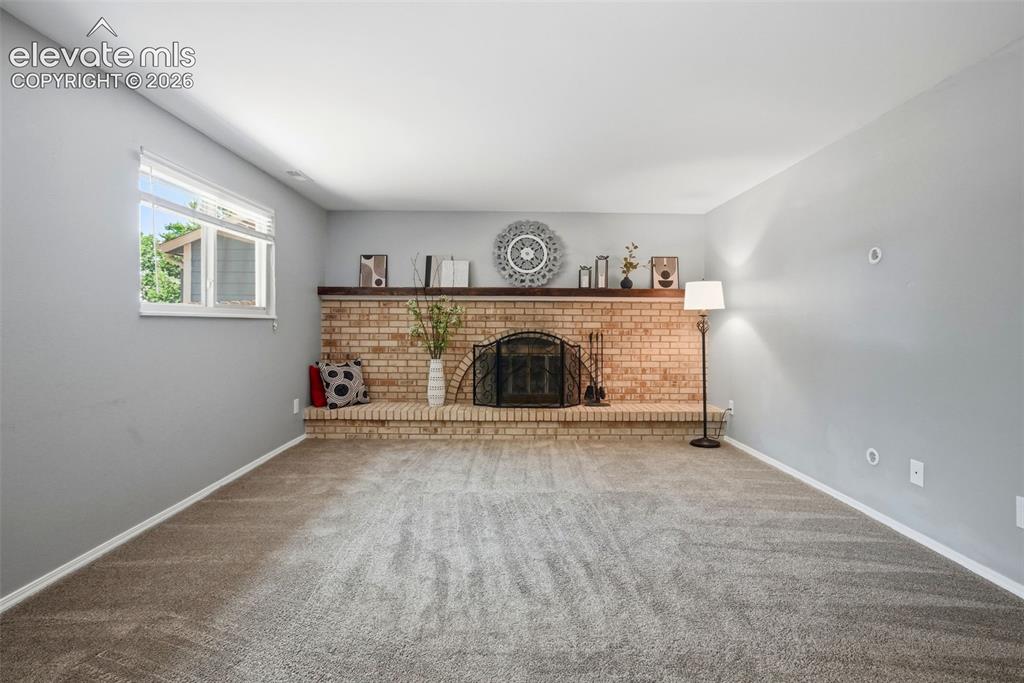 Image 16 of 50: Spacious room featuring a brick fireplace with a raised hearth, a wood mant
