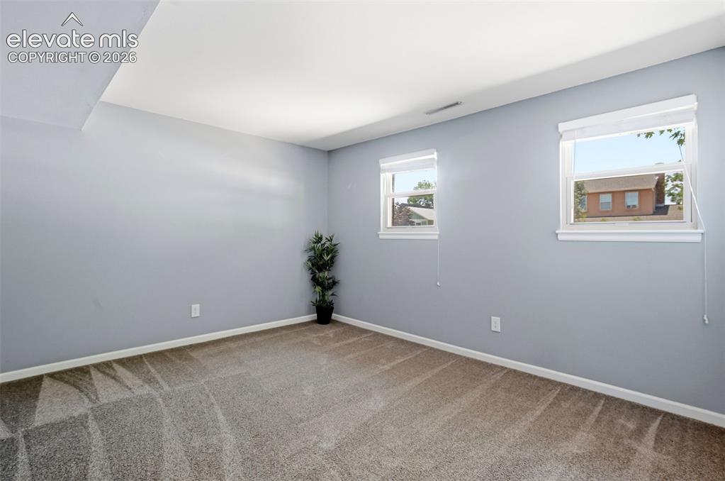 Image 22 of 50: Carpeted interior space with light gray walls, white trim, and two windows