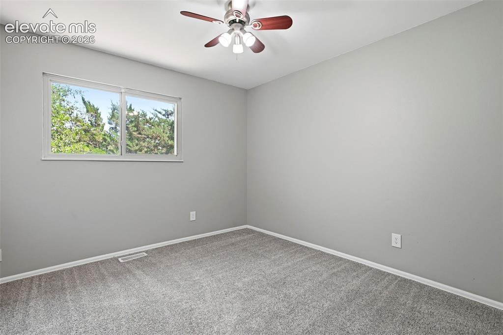 Image 27 of 50: Neutral-toned room featuring a window with exterior foliage, grey wall pain