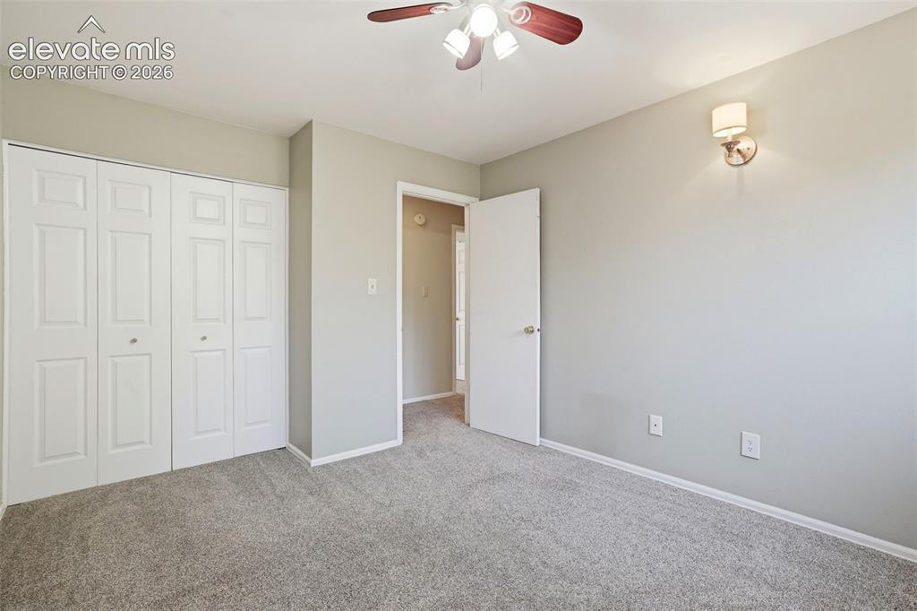 Image 28 of 50: Carpeted room featuring a ceiling fan with light fixture, bi-fold closet do