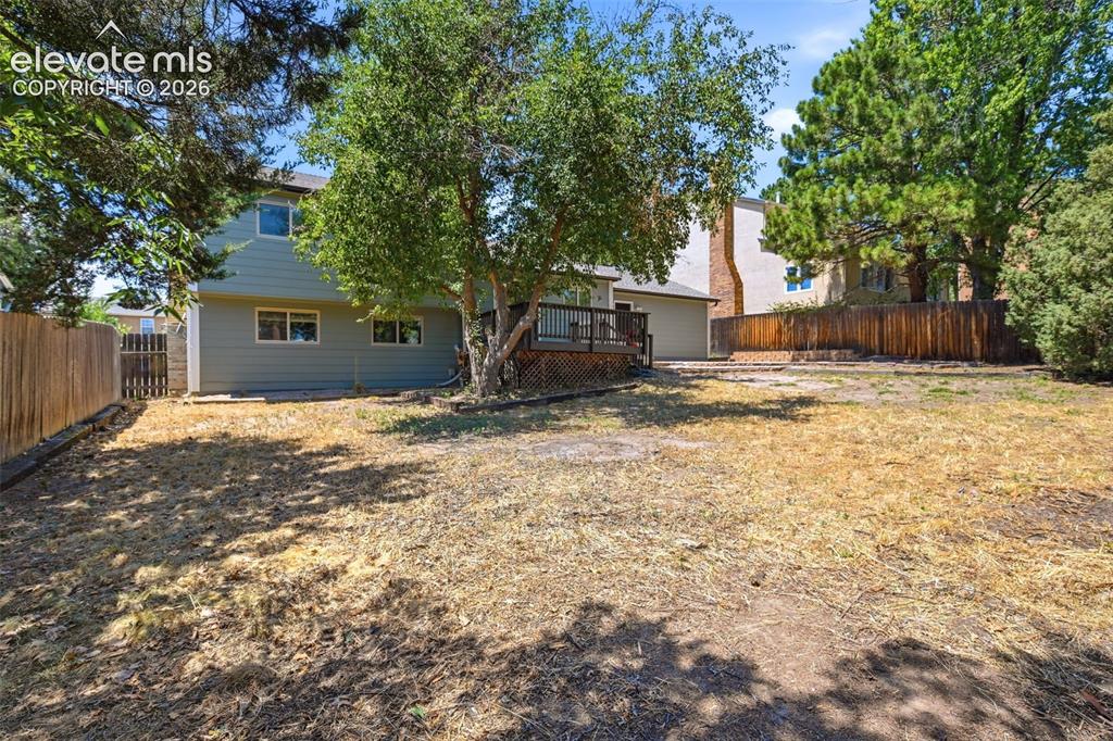 Image 39 of 50: Expansive backyard featuring a wood deck, mature trees, and a wooden privac