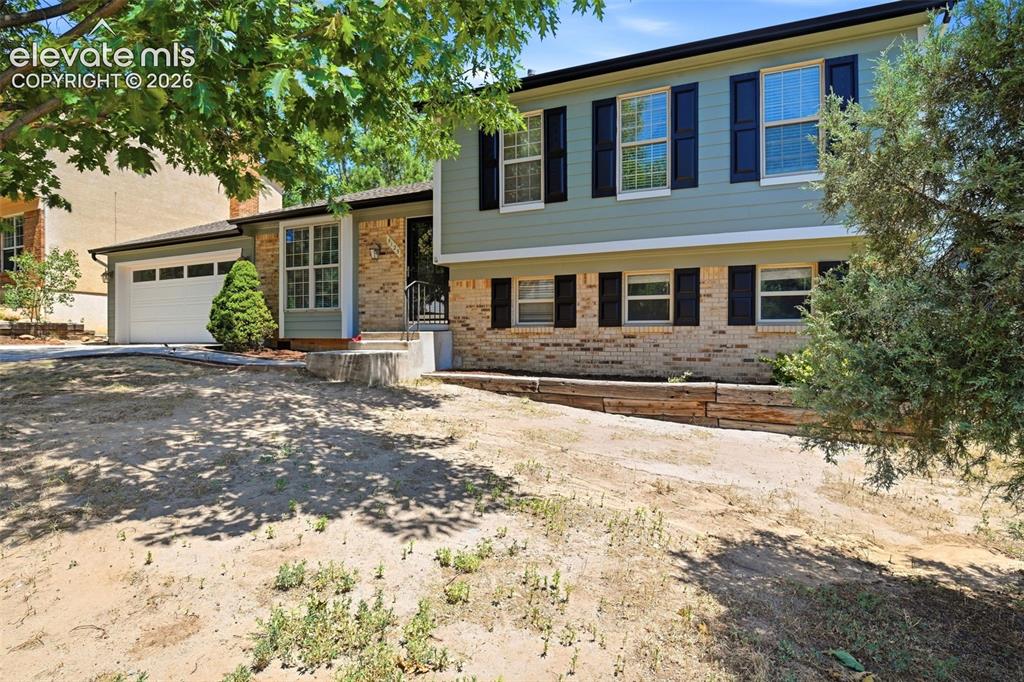 Image 40 of 50: Split-level residence featuring a brick and siding exterior with dark shutt