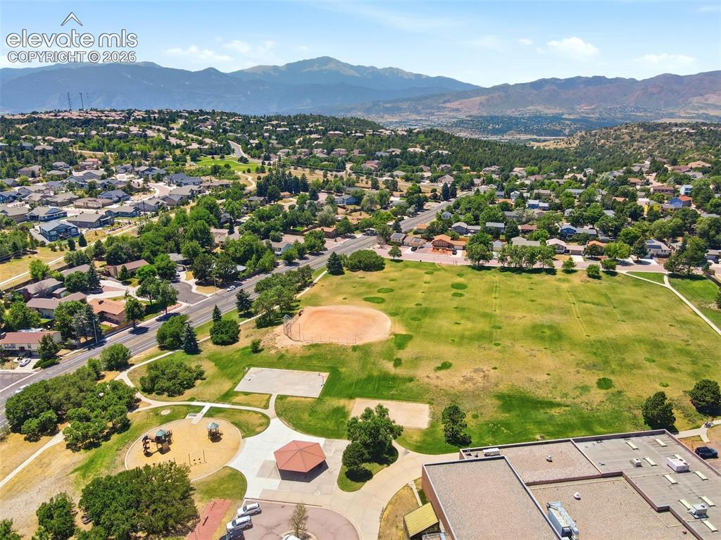 Image 43 of 50: Expansive green spaces featuring a baseball diamond, playground, and paved