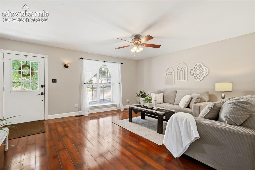Image 6 of 50: Living area featuring wood-finish flooring, a ceiling fan with light fixtur