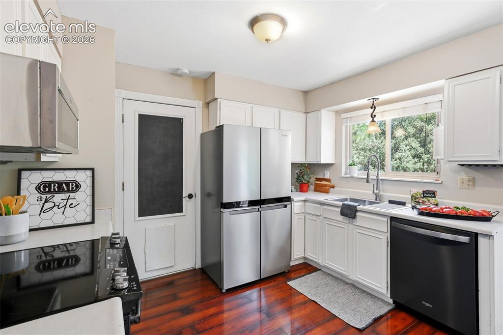 Image 9 of 50: Kitchen featuring rich wood-finish flooring, white cabinetry, and stainless