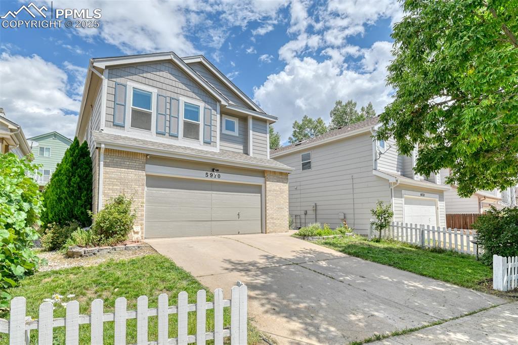 Caption: View of front of home featuring a garage, brick siding, and driveway