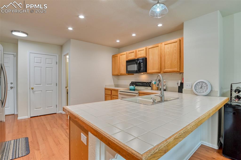 Image 11 of 43: Kitchen with light wood-type flooring, a breakfast bar area, recessed light