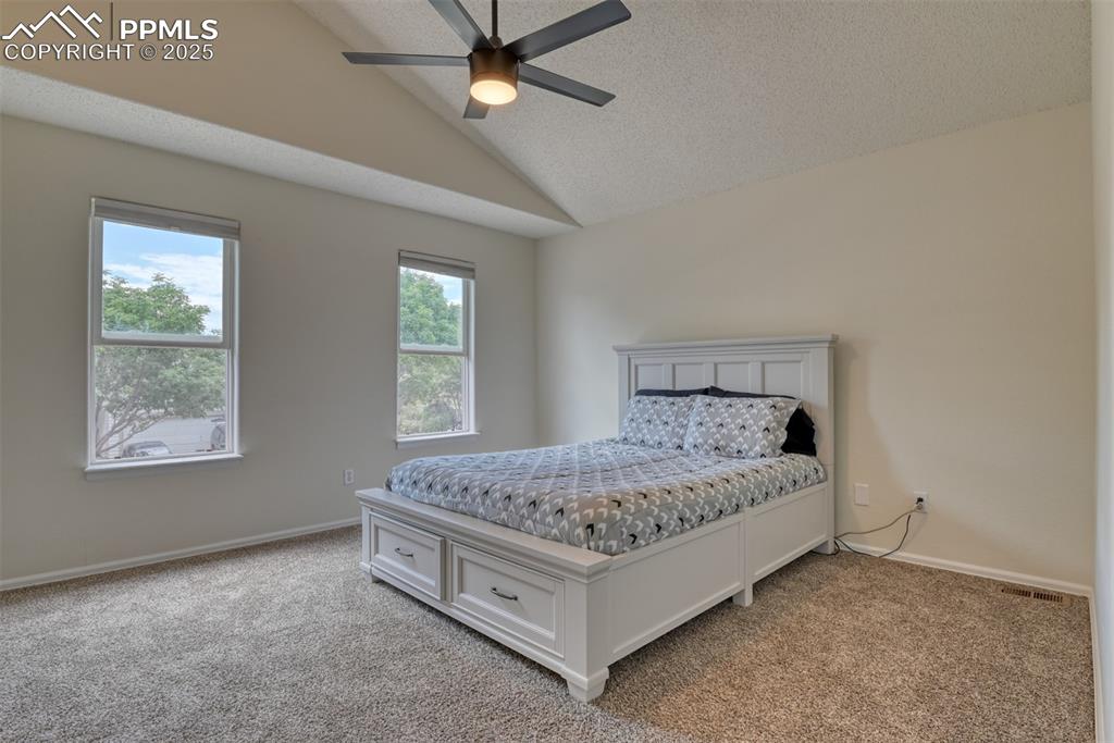 Image 18 of 43: Bedroom featuring vaulted ceiling, new carpet, new ceiling fan