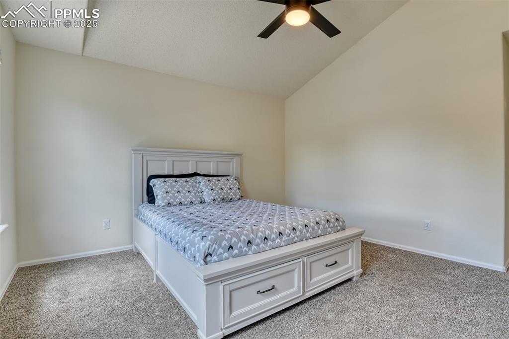 Image 21 of 43: Bedroom with vaulted ceiling, light colored carpet, and ceiling fan