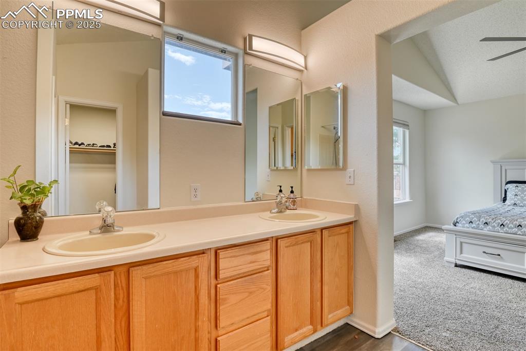 Image 23 of 43: Bathroom with vaulted ceiling, dual sinks and new flooring